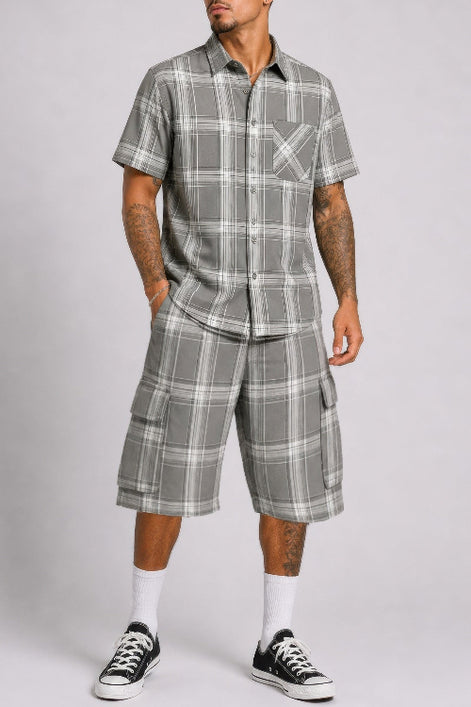 Man wearing a gray plaid shirt and shorts set on a plain background