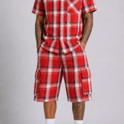 Person wearing a red plaid outfit with black Converse shoes on a gray background