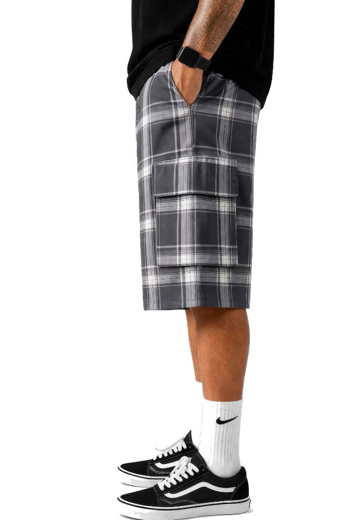 Person wearing plaid shorts and black sneakers on a white background