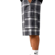 Person wearing plaid shorts and black sneakers on a white background