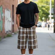 Person wearing brown plaid cargo shorts on a white background