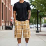 Person wearing plaid shorts and black sneakers on a white background