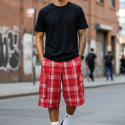 Person wearing red plaid cargo shorts with a white background