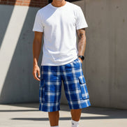 Person wearing blue plaid shorts, white socks, and black sneakers on a white background