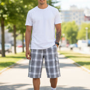 Person wearing plaid shorts, white socks, and black sneakers on a white background