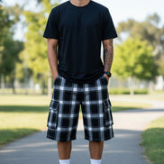 Person wearing black and white plaid cargo shorts on a white background