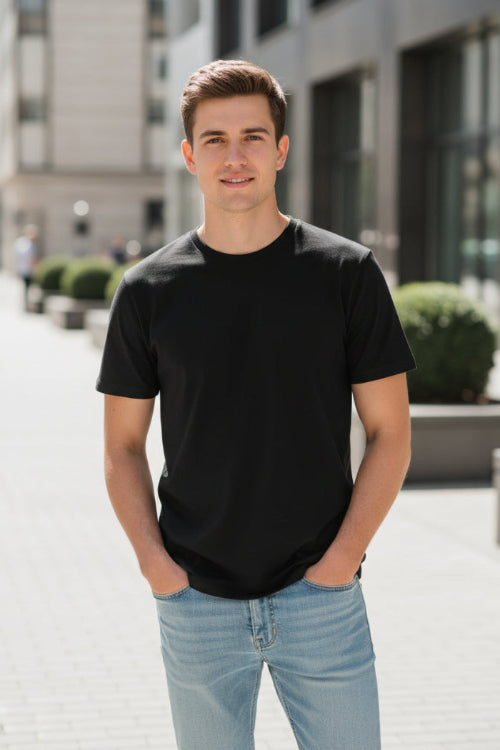Man wearing a black t-shirt and light blue jeans on a white background