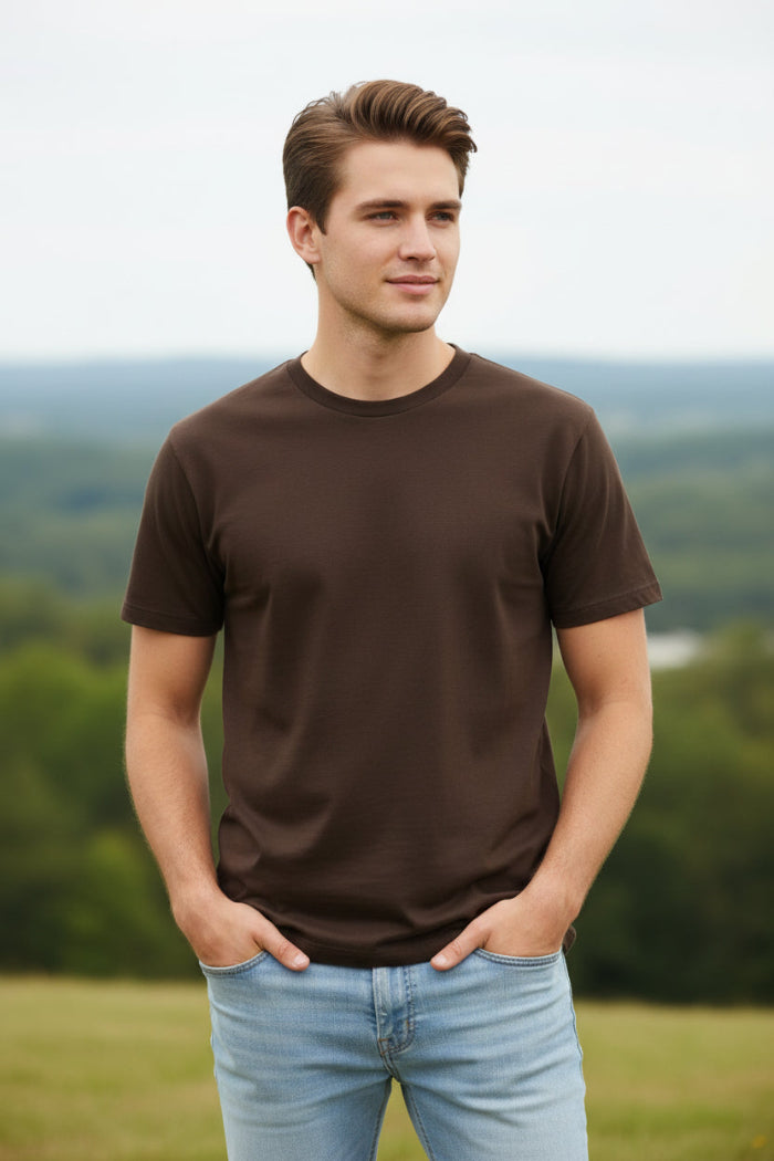 Man wearing a brown t-shirt and light blue jeans on a white background