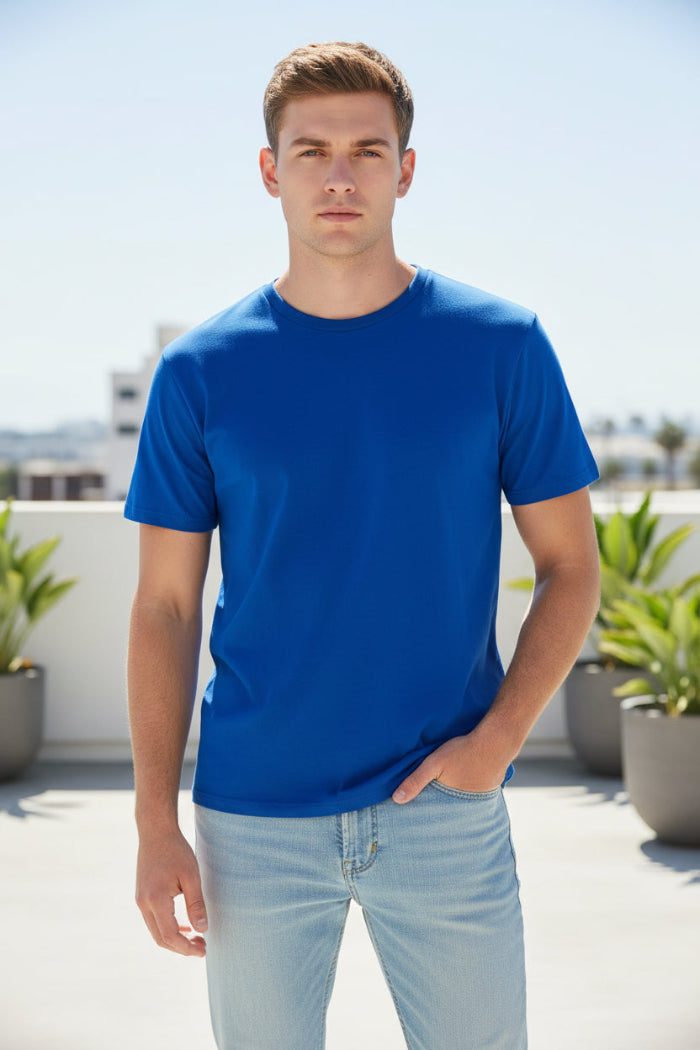 A man wearing a solid royal blue short-sleeve crewneck t-shirt and light wash jeans, shown from the chin down against a plain white background.