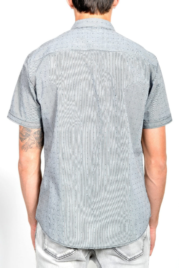 A man viewed from the back wearing a light gray short-sleeve button-down shirt with a subtle dotted pattern, paired with light gray jeans.