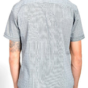 A man viewed from the back wearing a light gray short-sleeve button-down shirt with a subtle dotted pattern, 