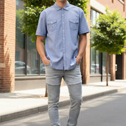 A man wearing a light blue short-sleeve button-up shirt with two chest pockets, 