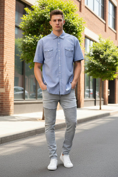 A man wearing a light blue short-sleeve button-up shirt with two chest pockets, 