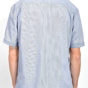 A man viewed from the back wearing a light blue short-sleeve button-down shirt with a subtle textured pattern, 