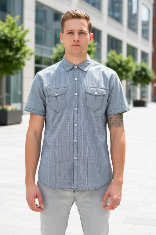 A man wearing a light gray short-sleeve button-up shirt with two chest pockets, 