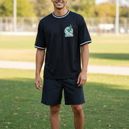 A man wearing a black short-sleeve t-shirt with white trim on the collar and cuffs, featuring a green and white Mexico national team crest 