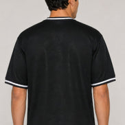 A man viewed from the back wearing a black short-sleeve t-shirt with white contrast trim on the collar 
