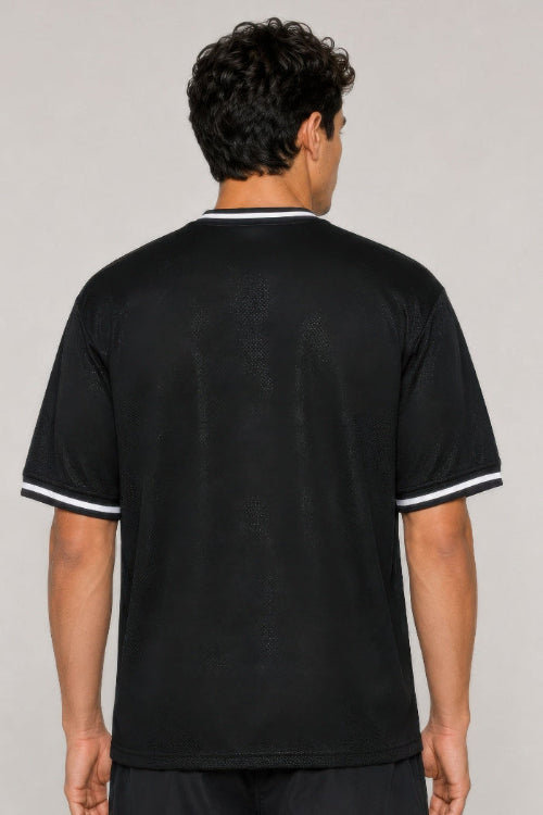 A man viewed from the back wearing a black short-sleeve t-shirt with white contrast trim on the collar 