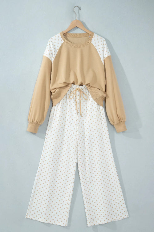 A two-piece women's lounge set hanging on a wooden hanger against a light gray wall. 