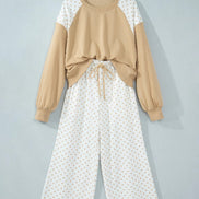 A two-piece women's lounge set hanging on a wooden hanger against a light gray wall. 
