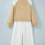 A two-piece pajama set hanging on a wooden hanger against a light gray wall. The set features a cropped long-sleeve sweatshirt 