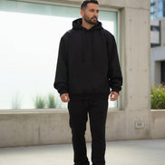 Person wearing a black hoodie and pants on a white background