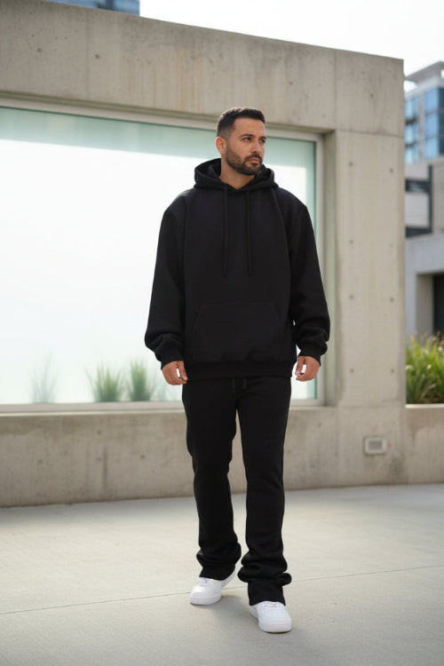 Person wearing a black hoodie and pants on a white background