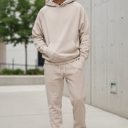 Person wearing a beige tracksuit on a white background