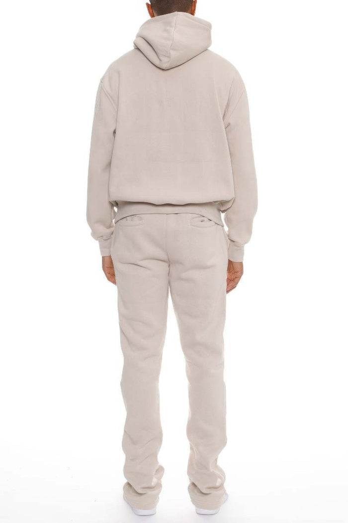 Person wearing a beige hoodie and pants set on a white background