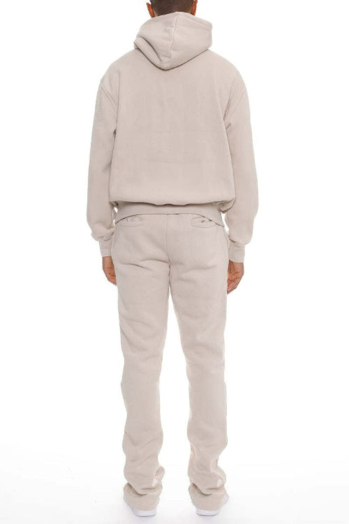 Person wearing a beige hoodie and pants set on a white background