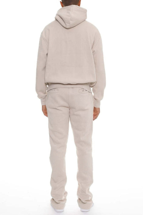 Person wearing a beige hoodie and pants set on a white background