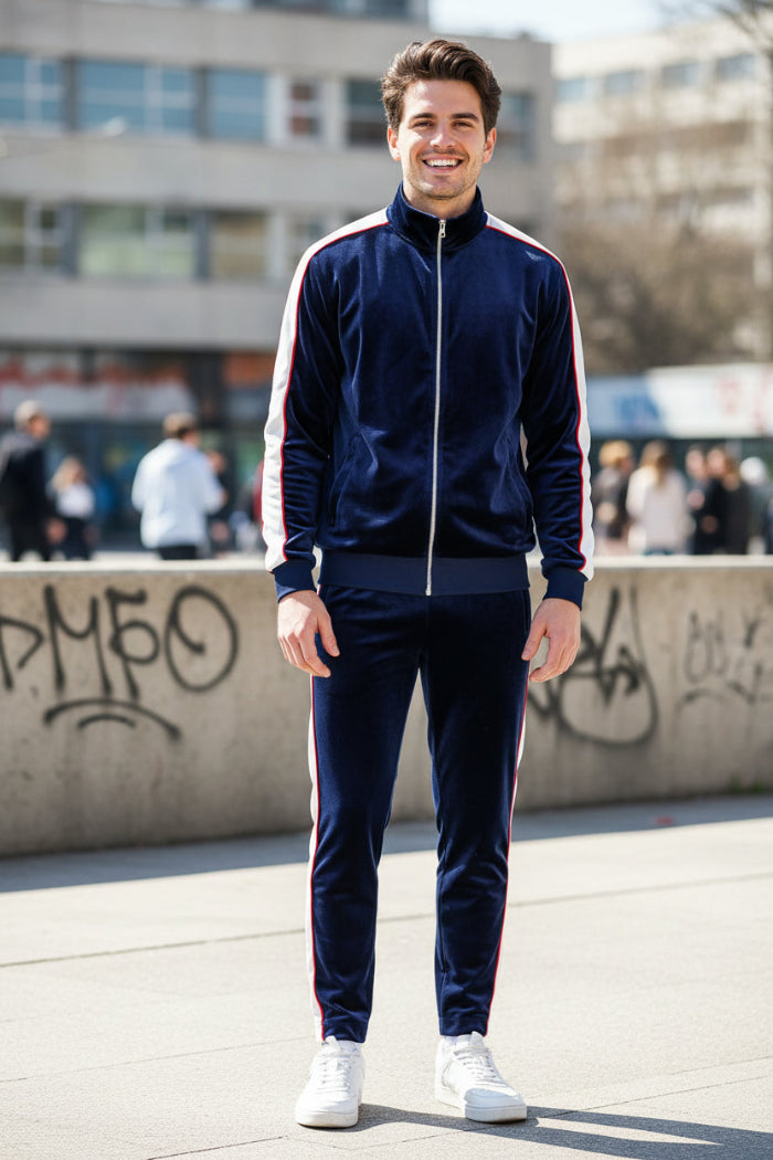 Man wearing a blue velvet tracksuit with white stripes  outside
