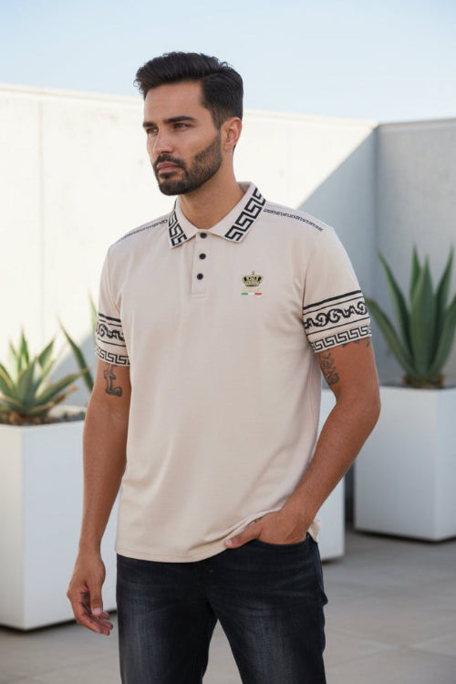 Man wearing a beige polo shirt with decorative patterns on sleeves and collar, standing against a white background.