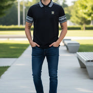 Black polo shirt with white patterns on sleeves and collar, featuring a logo, worn by a person.