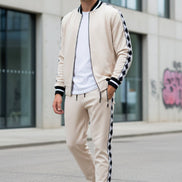 Man wearing a white bomber jacket and pants with black stripes outside