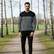 Man wearing a black and white striped sweater on a plain background
