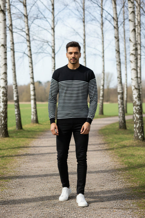 Man wearing a black and white striped sweater on a plain background