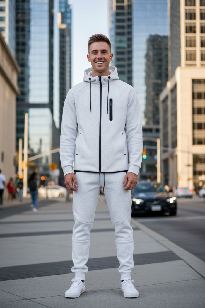 Man wearing a white tracksuit with black accents taken outside