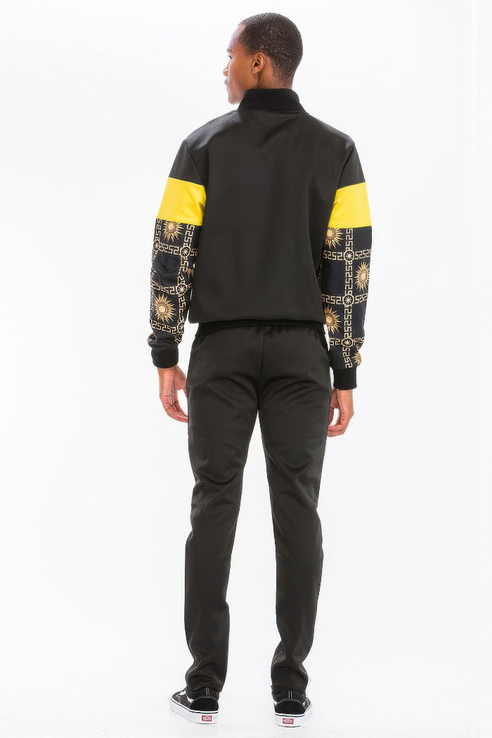 Person wearing a black and yellow jacket with patterned sleeves  taken outside