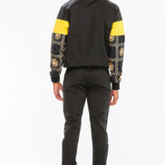 Person wearing a black and yellow jacket with patterned sleeves  taken outside