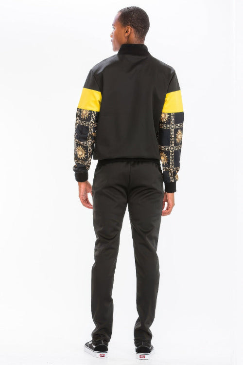 Person wearing a black and yellow jacket with patterned sleeves  taken outside