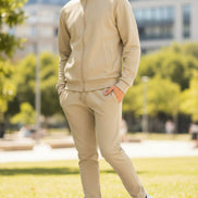 Man wearing a beige tracksuit with white sneakers  taken outside