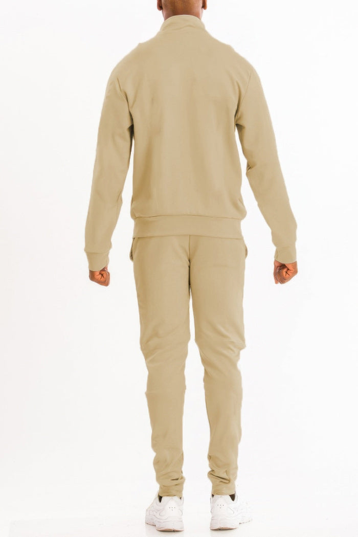 Person wearing a beige tracksuit on a white background
