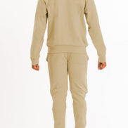Person wearing a beige tracksuit on a white background