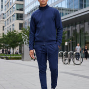 Man wearing a navy tracksuit with white sneakerstaken outside