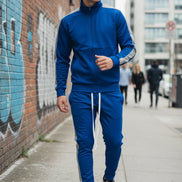 Man wearing a blue tracksuit with white stripes  taken outside