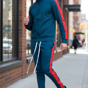 Man wearing a blue tracksuit with red stripes taken outside