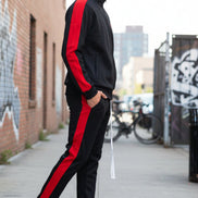 Person wearing a black tracksuit with red stripes  taken outside