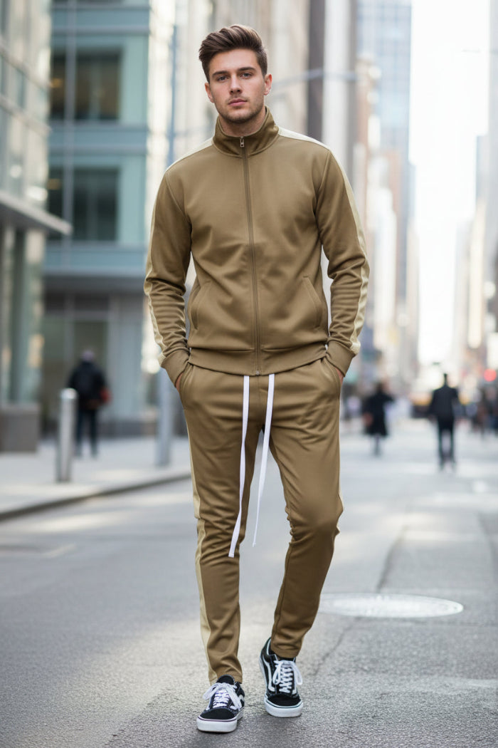 Man wearing a beige tracksuit with white stripes  taken outside