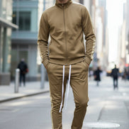 Man wearing a beige tracksuit with white stripes  taken outside